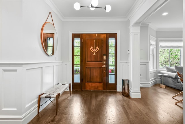 entrance foyer with a notable chandelier, a decorative wall, a wainscoted wall, and wood finished floors