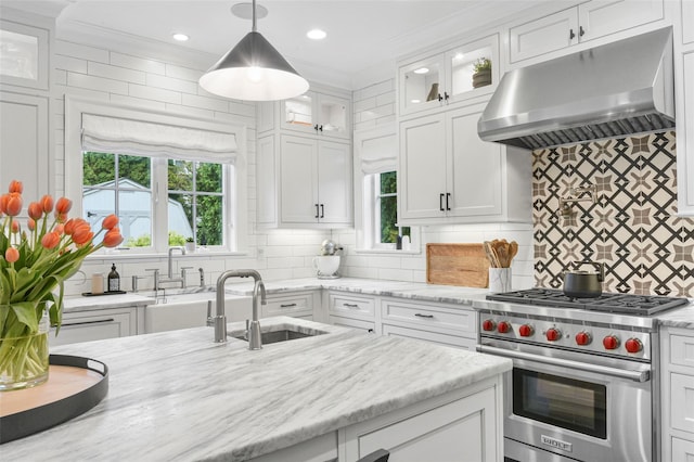 kitchen featuring under cabinet range hood, white cabinetry, premium stove, and a sink