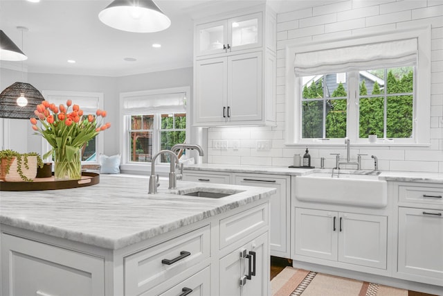 kitchen featuring white cabinetry, tasteful backsplash, light stone countertops, and a sink