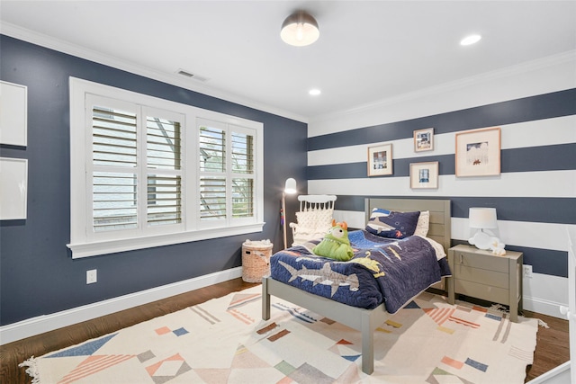 bedroom with wood finished floors, visible vents, baseboards, and ornamental molding