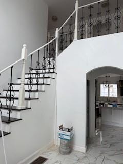 45 Manor Dr W, Poughkeepsie, NY 12603 - staircase featuring marble look tile flooring, arched walkways, baseboards, and a high ceiling
