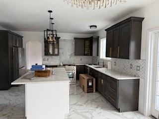 45 Manor Dr W, Poughkeepsie, NY 12603 - kitchen featuring a chandelier, light marble finish flooring, decorative backsplash, a kitchen island, and light countertops