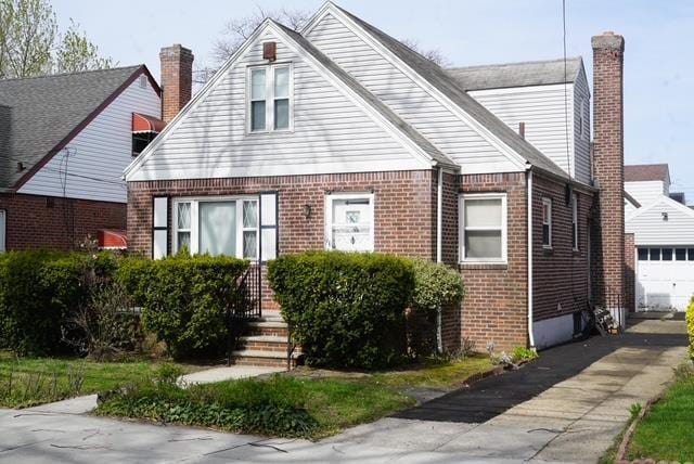 bungalow featuring a chimney, driveway, and brick siding