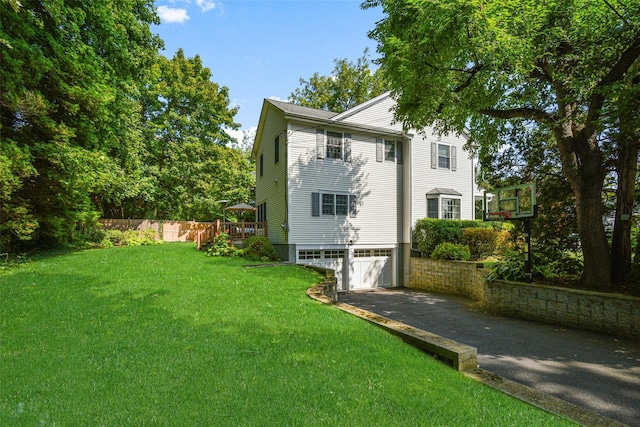 exterior space featuring a lawn, a garage, aphalt driveway, and a deck