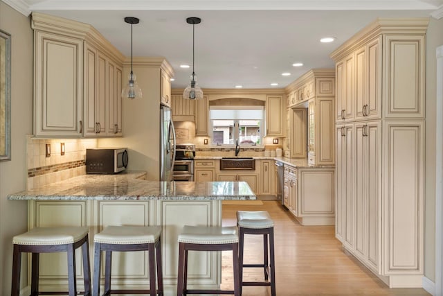 24 Akron Pl, Shoreham, NY 11786 - kitchen featuring appliances with stainless steel finishes, a peninsula, cream cabinets, a sink, and light wood-style flooring