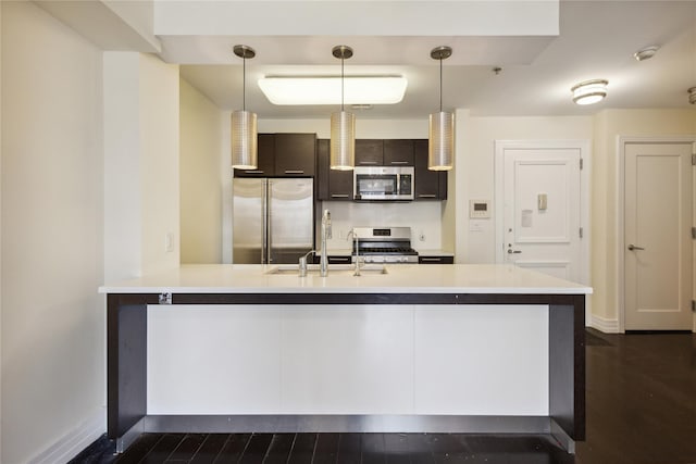kitchen with light countertops, stainless steel appliances, a sink, and a peninsula
