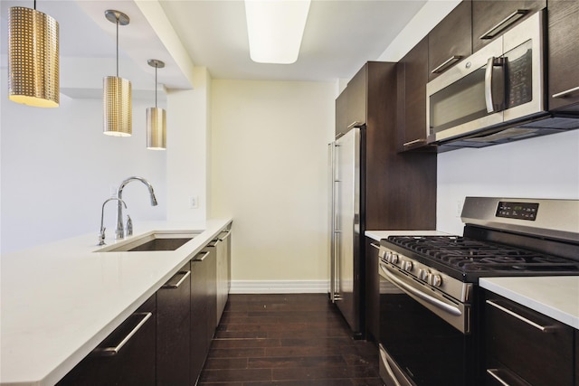 kitchen with dark brown cabinetry, light countertops, a sink, dark wood finished floors, and stainless steel appliances