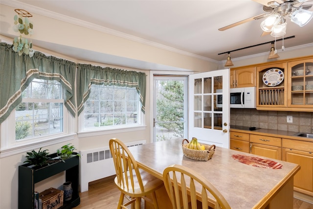 dining area with crown molding, radiator heating unit, ceiling fan, and light wood-style floors