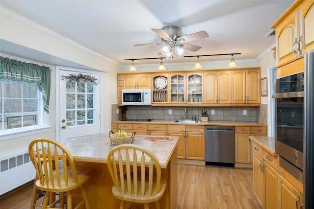 kitchen featuring white microwave, track lighting, a breakfast bar area, light wood-type flooring, and stainless steel dishwasher