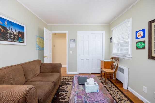 living area with baseboards, ornamental molding, wood finished floors, and radiator