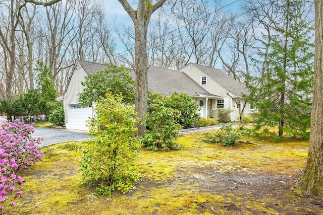 view of front of home featuring an attached garage, roof with shingles, and aphalt driveway
