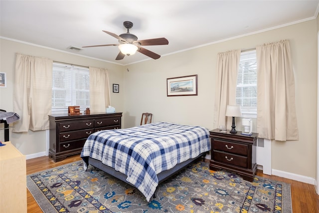bedroom featuring visible vents, crown molding, and wood finished floors