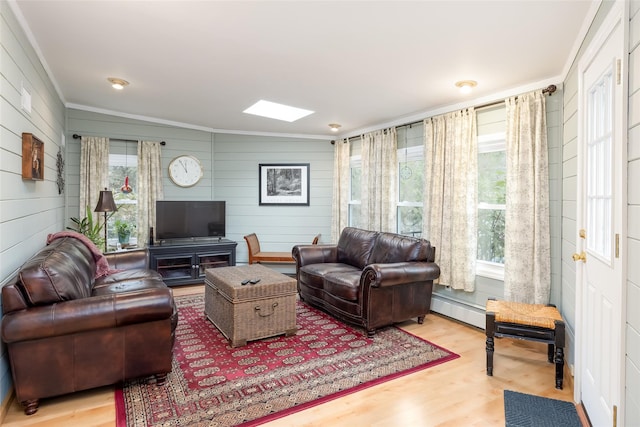 living room with baseboard heating, ornamental molding, a wealth of natural light, and wood finished floors