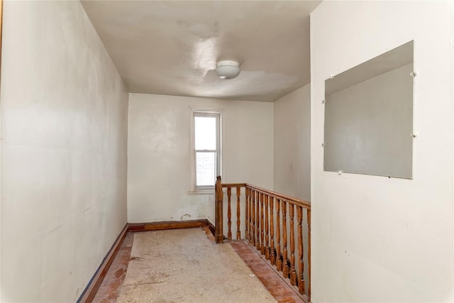hall with baseboards and an upstairs landing