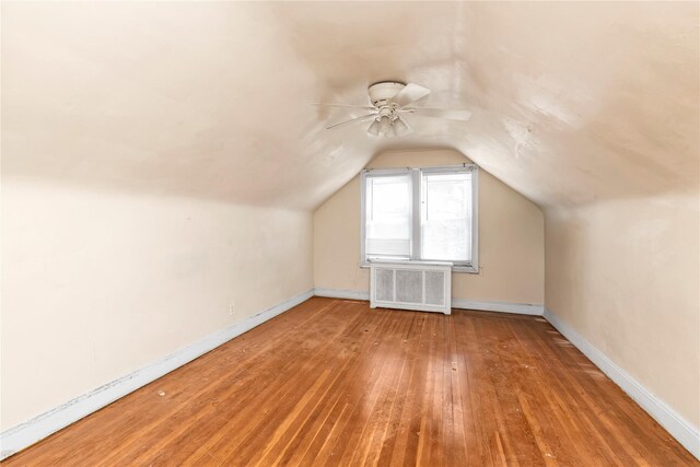 bonus room with ceiling fan, vaulted ceiling, baseboards, radiator, and hardwood / wood-style floors