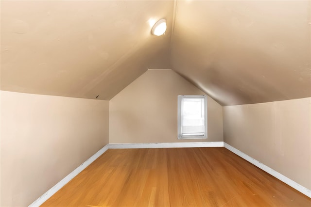 additional living space featuring baseboards, vaulted ceiling, and light wood-style floors