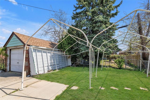 view of yard featuring a garage, fence, an outbuilding, and concrete driveway