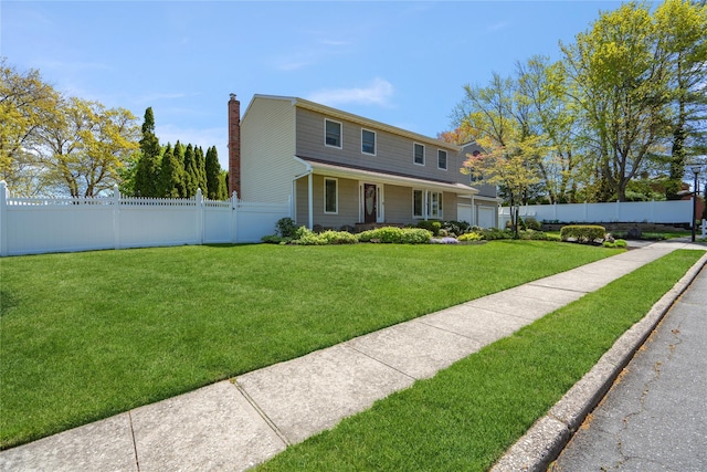 view of front of home with a garage, a chimney, fence private yard, and a front lawn