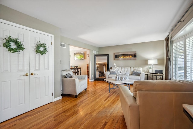 living area featuring visible vents, light wood-style flooring, and baseboards