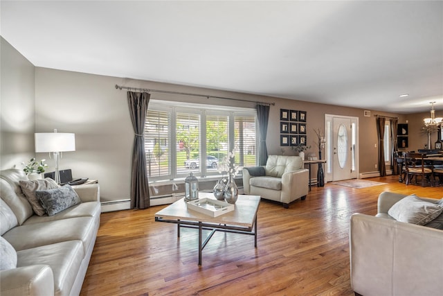 living room featuring baseboard heating, wood finished floors, and a chandelier