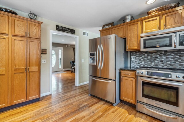 kitchen with brown cabinets, appliances with stainless steel finishes, light wood finished floors, and visible vents