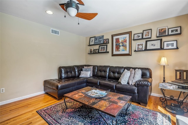 living room featuring visible vents, a ceiling fan, baseboards, and wood finished floors