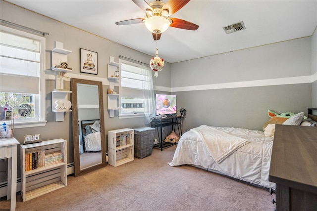 carpeted bedroom featuring a ceiling fan, visible vents, and a baseboard radiator