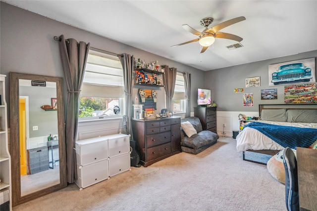 bedroom featuring visible vents, carpet flooring, a ceiling fan, and a wainscoted wall