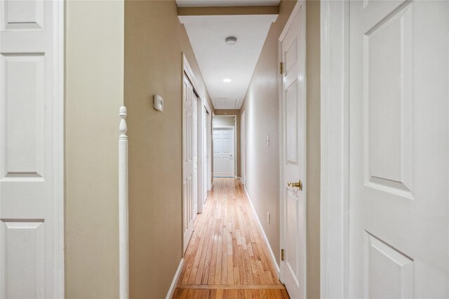 hall featuring light wood-style floors, baseboards, attic access, and recessed lighting