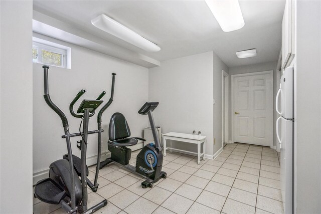 exercise room with light tile patterned floors and baseboards