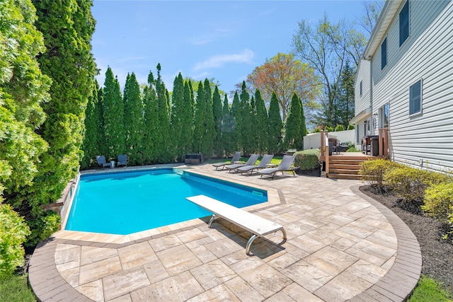 pool with a wooden deck, a diving board, and a patio area