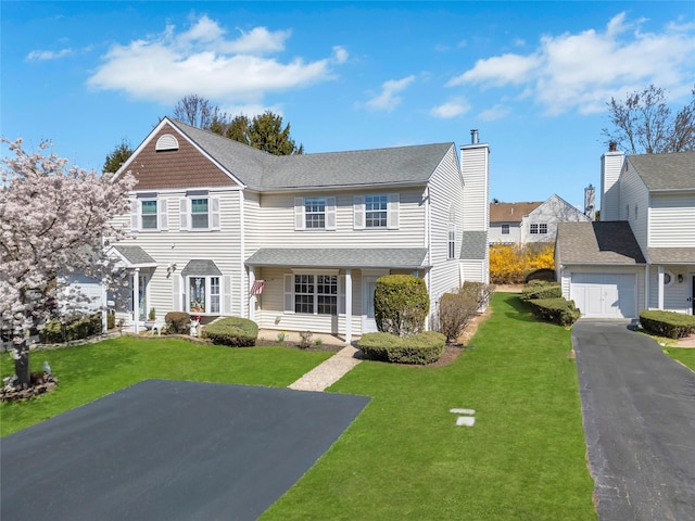 view of front facade featuring a chimney, a front lawn, and aphalt driveway