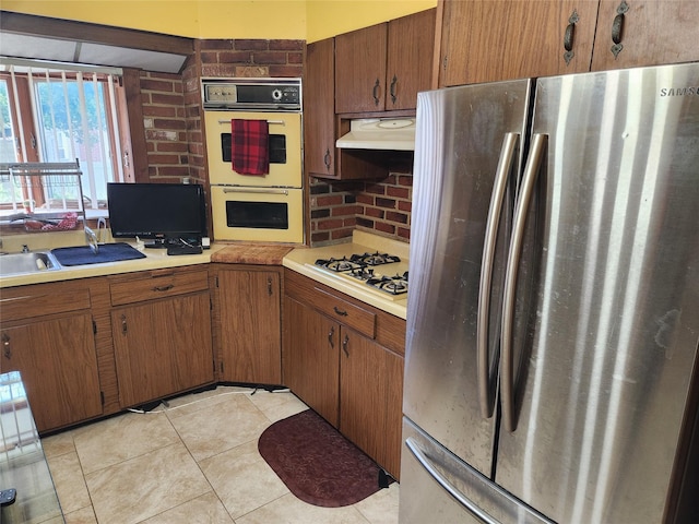112 Rutland Rd, Hempstead, NY 11550 - kitchen with freestanding refrigerator, multiple ovens, under cabinet range hood, white gas stovetop, and light countertops