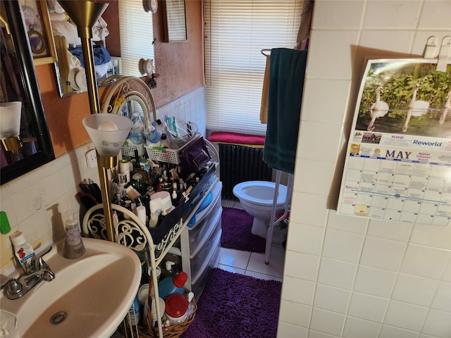 112 Rutland Rd, Hempstead, NY 11550 - bathroom with radiator, tile walls, a sink, toilet, and tile patterned flooring