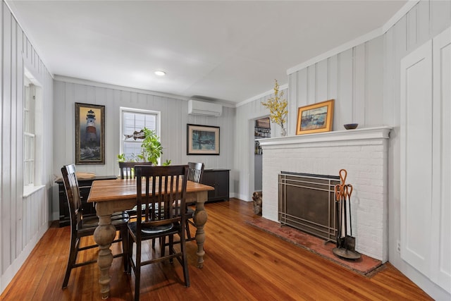 dining area with wood finished floors, ornamental molding, a fireplace, and an AC wall unit