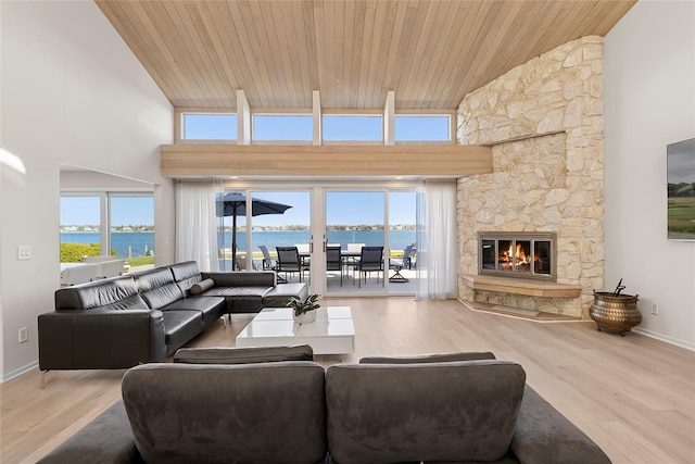 living room featuring wood finished floors, a water view, wood ceiling, a fireplace, and high vaulted ceiling