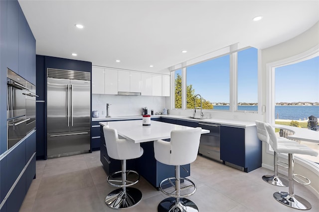 kitchen featuring a water view, a sink, modern cabinets, a kitchen bar, and appliances with stainless steel finishes
