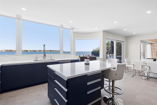 kitchen featuring a center island, a sink, a kitchen bar, modern cabinets, and light countertops