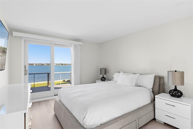 bedroom featuring light wood-style floors, a water view, and access to exterior