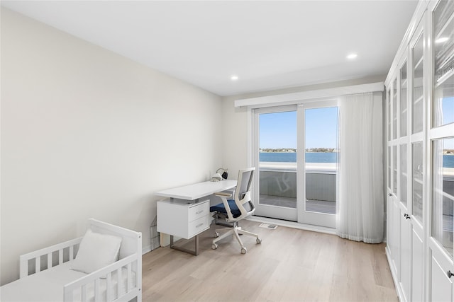 office with recessed lighting, visible vents, a water view, and light wood-style flooring