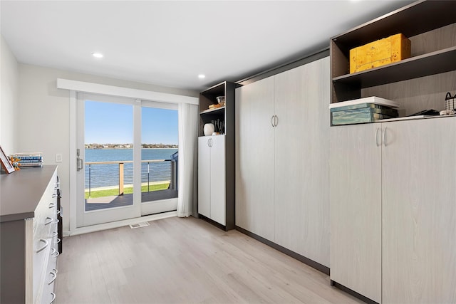 interior space featuring recessed lighting, visible vents, light wood finished floors, and a water view