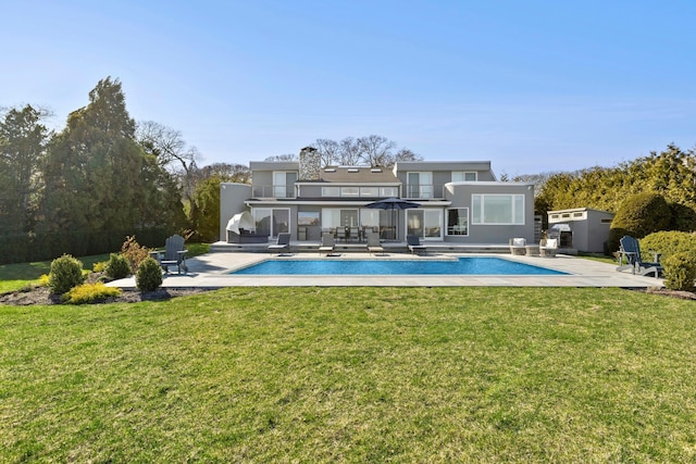 rear view of house featuring stucco siding, an outdoor pool, a patio, and a lawn