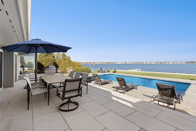 outdoor pool with a patio area, outdoor dining area, and a water view
