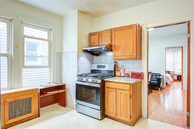 121-41 6th Ave, College Point, NY 11356 - kitchen with light stone countertops, decorative backsplash, gas range, and under cabinet range hood