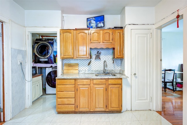 121-41 6th Ave, College Point, NY 11356 - kitchen with light stone counters, a sink, brown cabinetry, stacked washer / drying machine, and backsplash