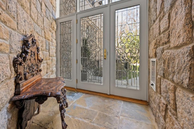 doorway to outside with stone tile floors and plenty of natural light