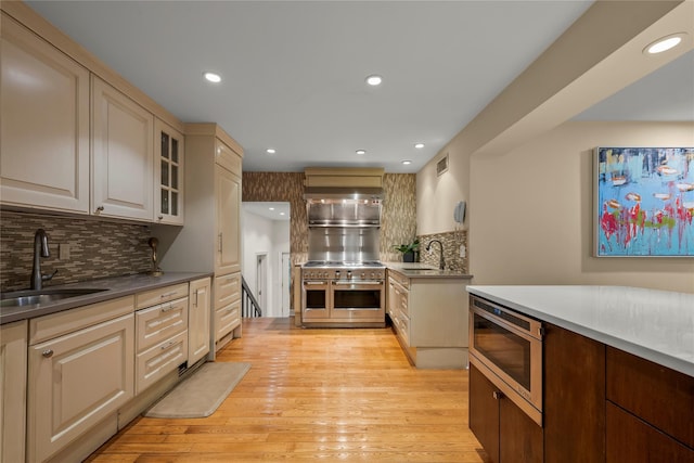 kitchen with tasteful backsplash, a sink, light wood-style floors, stainless steel appliances, and visible vents