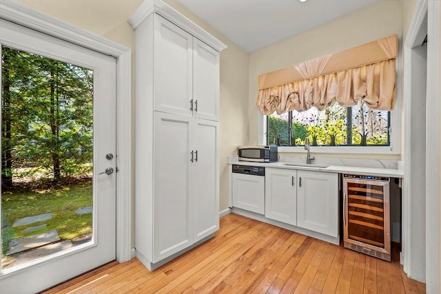 bar with stainless steel microwave, a sink, white dishwasher, light wood-type flooring, and wine cooler