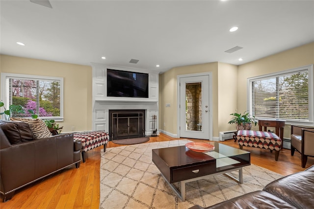 living room with a fireplace, recessed lighting, light wood-style floors, and a baseboard radiator