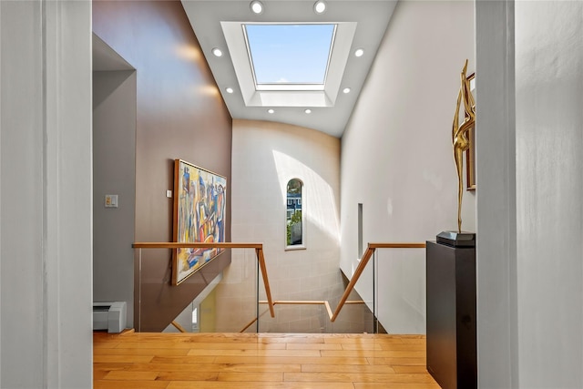 hallway featuring recessed lighting, an upstairs landing, a skylight, wood finished floors, and a baseboard radiator